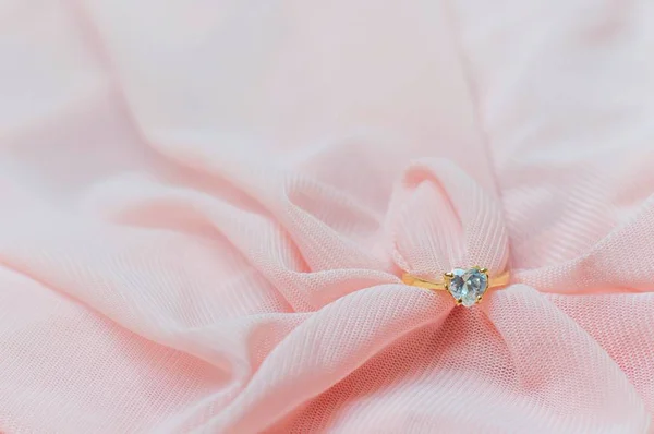 Close up of diamond ring on pink fabric for valentine day or wedding background