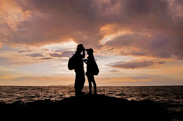 夕暮れ時にビーチで手をつないでいるカップルのシルエット — ストック写真