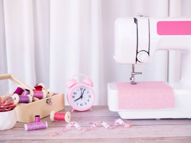 Pembe kumaşla çalışan dikiş makinesini kapatın, masaya aksesuarlar dikin, yeni kıyafetler dikin..