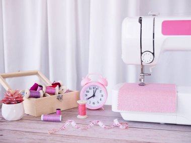 Pembe kumaşla çalışan dikiş makinesini kapatın, masaya aksesuarlar dikin, yeni kıyafetler dikin..