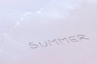 Kumlu bir sahilde el yazısıyla okyanus dalgalarıyla yazılmış yazılar..