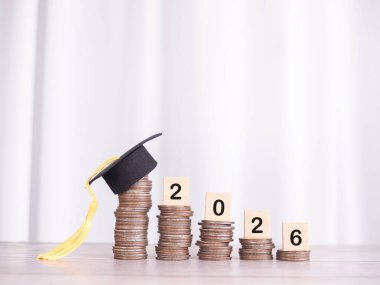 2026 numaralı tahta bloklar ve mezuniyet şapkalı bozuk paralar. 2026 yılında eğitim, öğrenci kredisi, burs, öğrenim ücreti için para biriktirme kavramı