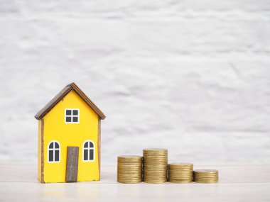 Minyatür ev ve bozuk para yığını. Ev için para biriktirme kavramı, emlak yatırımları, ev kredisi, gelecekte gayrimenkul.