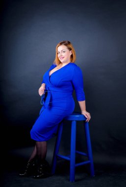 Siyah bir zemin üzerine mavi şık elbiseli güzel tombul kız. Seksi artı boyutu kadın