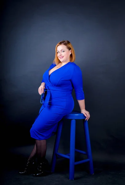 Siyah bir zemin üzerine mavi şık elbiseli güzel tombul kız. Seksi artı boyutu kadın