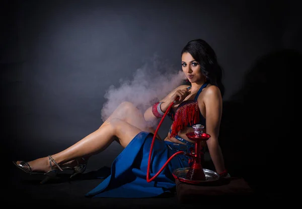 Seksi bir kostüm güzel bir oryantal kız Portresi. kız yere oturur, bir nargile içer ve duman nefes