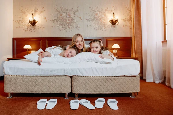 Mutlu anne ve çocuk ikiz yatakta rahat otel odasında sarılma.