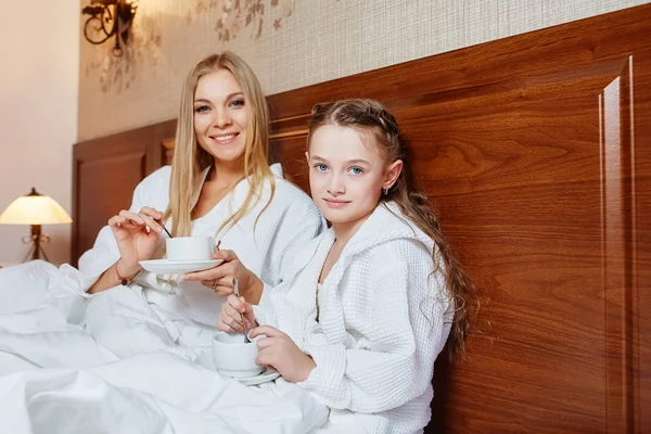 Gülümseyen anne ve çocuk bir rahat otel odasında yatakta kahvaltı edelim. Aile, sevgi, bakım kavramı