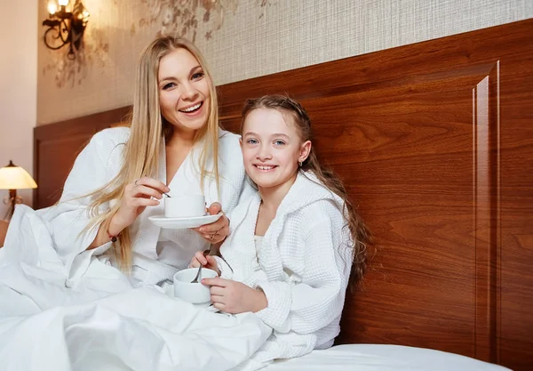 Gülümseyen anne ve çocuk bir rahat otel odasında yatakta kahvaltı edelim. Aile, sevgi, bakım kavramı
