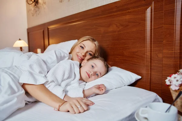 Mooie moeder en de dochter omarmen en liggen in een bed — Stockfoto