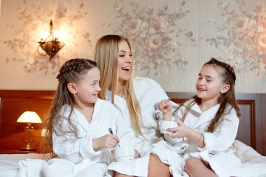 gülümseyen ikiz kız annesi ile kahvaltı yem. Gül bakalım, rahat oda oturmak.