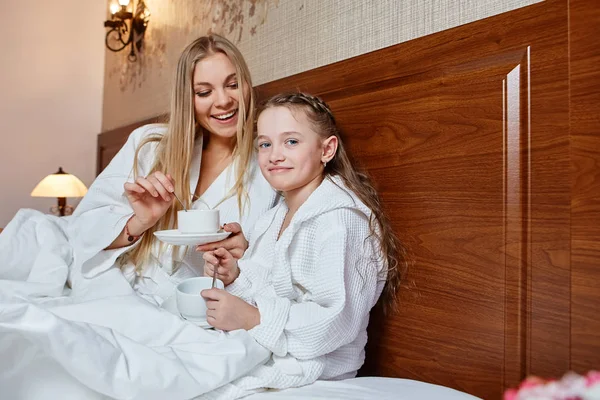 Smiling mother and child have Breakfast in bed, in a cozy hotel room. The concept of family, love, care