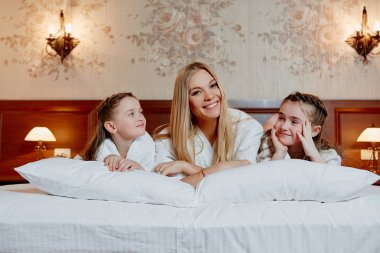 Bir anne ve çocukları bir yatakta yatarken portresi