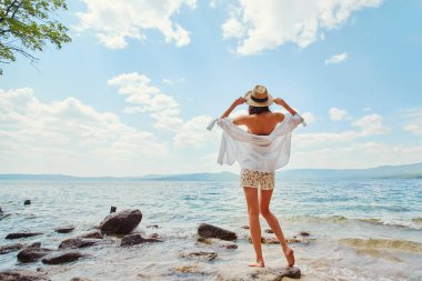 Suyun kenarında bir beyaz gömlek ve şapka ince bir kadında rahatlatır.