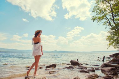 güzel ince kız rahatlatıcı bir büyük göl kayalık plaj.