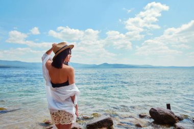 Suyun kenarında bir beyaz gömlek ve şapka ince bir kadında rahatlatır.