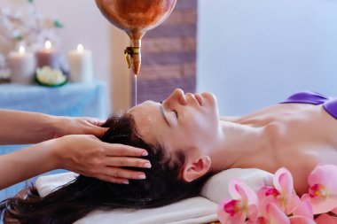 Dökme yağı masaj spa tedavisi olan genç bir kadın. Shirodhara dökülen yağlı kafa. Kafa tedavisinde