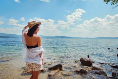 güzel ince kız rahatlatıcı bir büyük göl kayalık plaj.