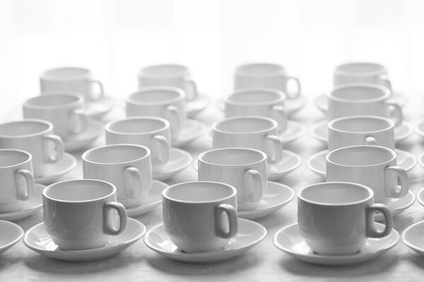 Белые чашки для чая, сложенные в ряд на столе со скатертью для
