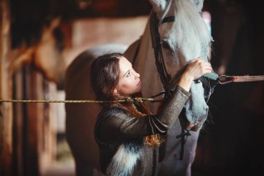 Genç bir kız bir köy ahır içinde onun atı eyerleyin
