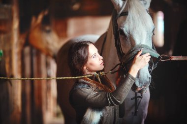 Genç bir kız bir köy ahır içinde onun atı eyerleyin
