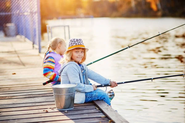 Kleine meisjes vissen op het meer, zittend op een houten ponton — Stockfoto