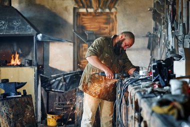 Acımasız çalışan bir açı değirmeni bir forge atölye ile bir detay keser.