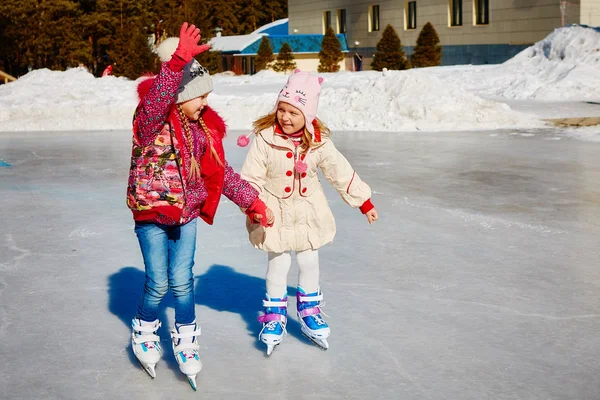 小女孩学滑冰 他们笑着高兴 友谊和有趣的节日的概念 免版税图库照片