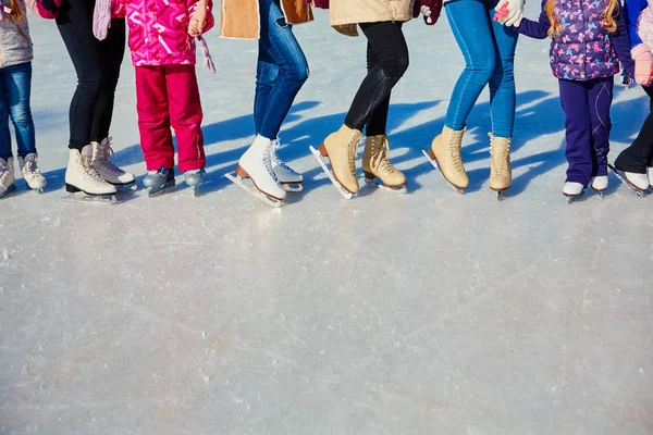 Close-up of the skates from the skaters on the ice surface. Skate on the ice in the company of friends. Skate rental. Place for text. — Stock Photo, Image