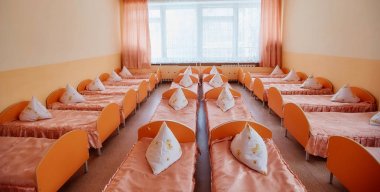 Beds and cots in brightly colored dormitory of a nursery.A lot of childrens cots clipart