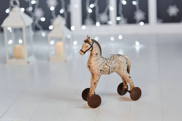 Toy wooden horse on wheels on the background of lights garland o
