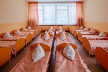 Beds and cots in brightly colored dormitory of a nursery.A lot of children's cots clipart