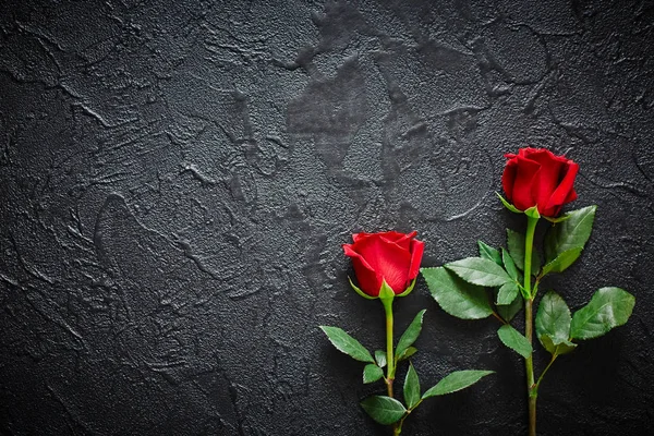 Δύο κόκκινα τριαντάφυλλα σε ένα σκοτεινό, μαύρο πέτρινο φόντο. Θέση για κείμενο — Φωτογραφία Αρχείου