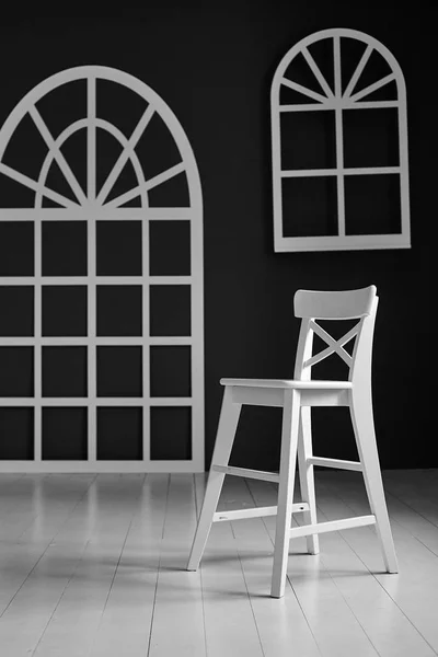 Bílá židle na tmavém pozadí. Stěna je vyzdobena podrobnostmi ve tvaru klenutého dveří a klenutým systémem Windows. — Stock fotografie