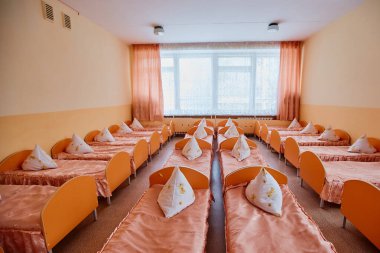 Beds and cots in brightly colored dormitory of a nursery.A lot of childrens cots clipart