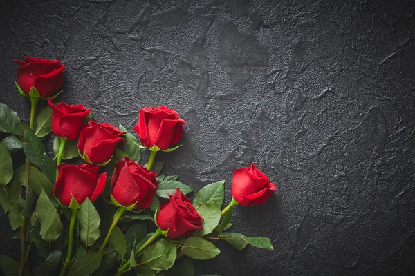 Червоні троянди на чорному, текстурованому, кам'яному фоні. Місце для тексту, вид зверху — стокове фото