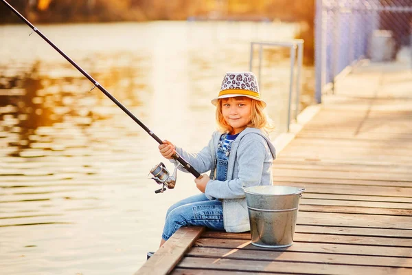 Una niña pescando con una caña de pescar de un pontón o muelle en la piscifactoría del estanque — Foto de Stock