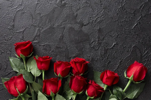 Червоні троянди на чорному, текстурованому, кам'яному фоні. Місце для тексту — стокове фото