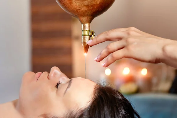 Ayurveda massaggio terapia curativa alternativa. bella femmina caucasica ottenere trattamento shirodhara sdraiato su un tavolo di legno in salone India . — Foto Stock