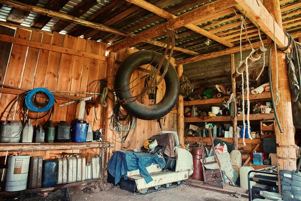 Stara drewniana szopa na odległym kordonie, z narzędziem do naprawy sprzętu, z grupą starych kanistrów i cylindrów do tankowania i smarowania skuterów śnieżnych i Atvs. — Zdjęcie stockowe