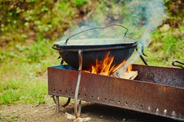 Bir turist otoparkında şömine ve yakacak odunuyla metal bir kazan duruyor.