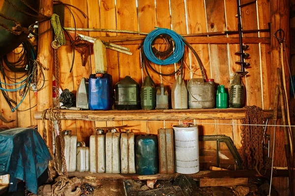 Un grupo de viejos recipientes y cilindros están sobre estantes en un cobertizo de madera . —  Fotos de Stock