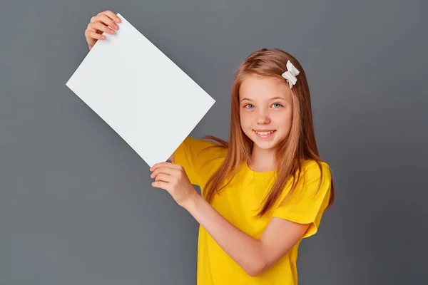 小宝宝拿着一张白色的床单 可爱的小女孩拿着一张白色的纸 灰色背景 文字空间 一个小女孩手里拿着一张空纸片 — 图库照片