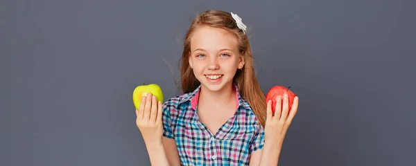 一个可爱的小女孩在灰色背景的绿色苹果和红色苹果之间做出选择 选择或作出困难决定的概念 — 图库照片
