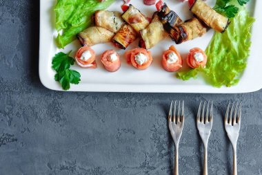 Soğuk mezeler, kanepeler ve rulo balıklar, patlıcan ve jambon, taze otlarla süslenmiş..