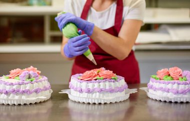 Pasta şefi pastaları süslemek için kremadan çiçek yapar.
