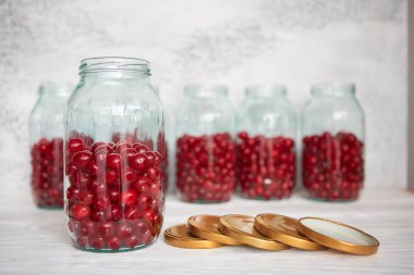 Not closed glass jars with cherries, prepared for canning with tin screw lids clipart