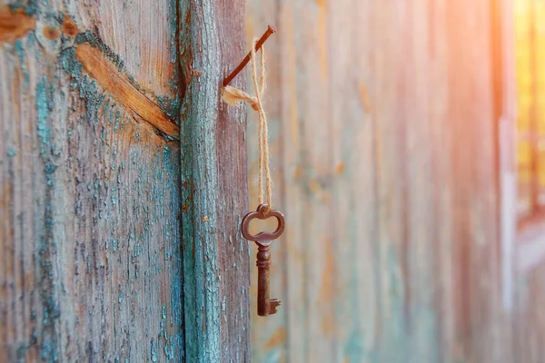 กุญแจสนิมวินเทจแขวนอยู่บนตะปูบนผนังของบ้านเก่าในตอนเช้า . — ภาพถ่ายสต็อก