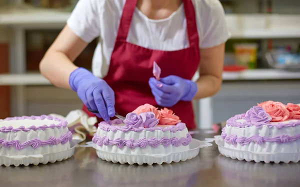 The process of decorating cakes in a pastry shop. A pastry chef makes flowers out of cream