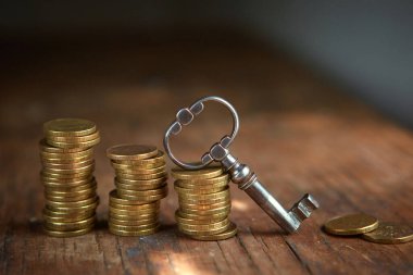 Eski güzel bir antika anahtar ve bir yığın altın para. Girişim, yatırım, hazine avı ya da başarının anahtarı.